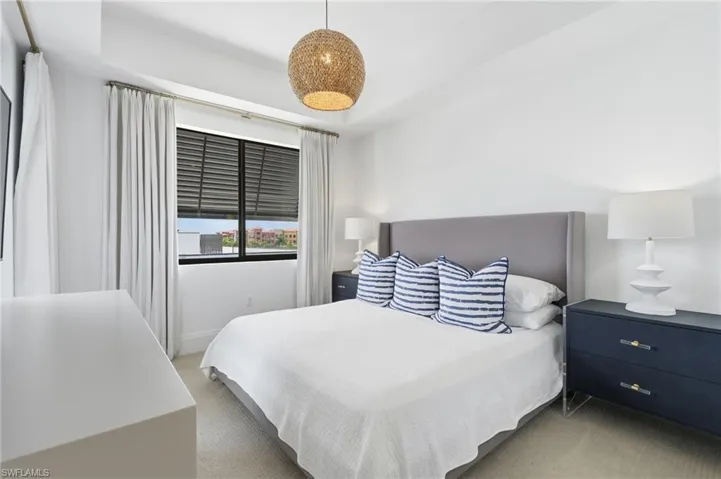 Woven pendant light fixture, large window with blinds and drapes, and a built-in wall-mounted television