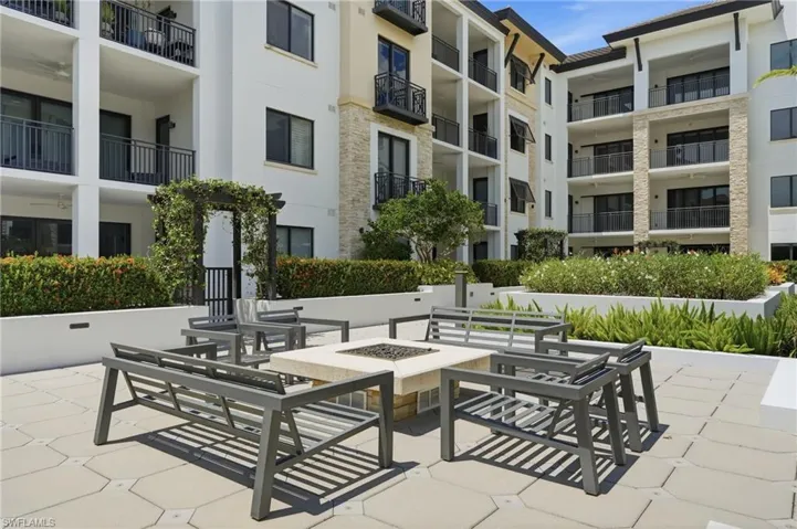 Paver patio with a central fire pit, surrounded by built-in planters and manicured landscaping