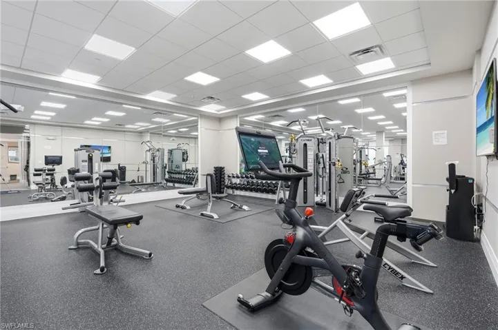 Fitness center with mirrored walls, recessed lighting, and rubberized flooring