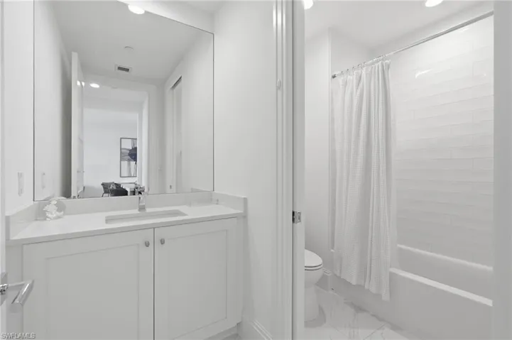 White shaker-style vanity with a light-toned countertop, undermount sink, and polished chrome faucet