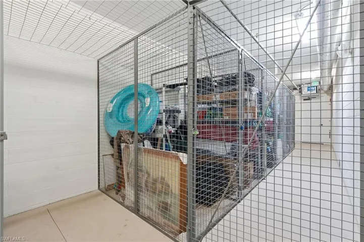 Wire mesh storage unit with concrete block walls, overhead lighting, and concrete flooring
