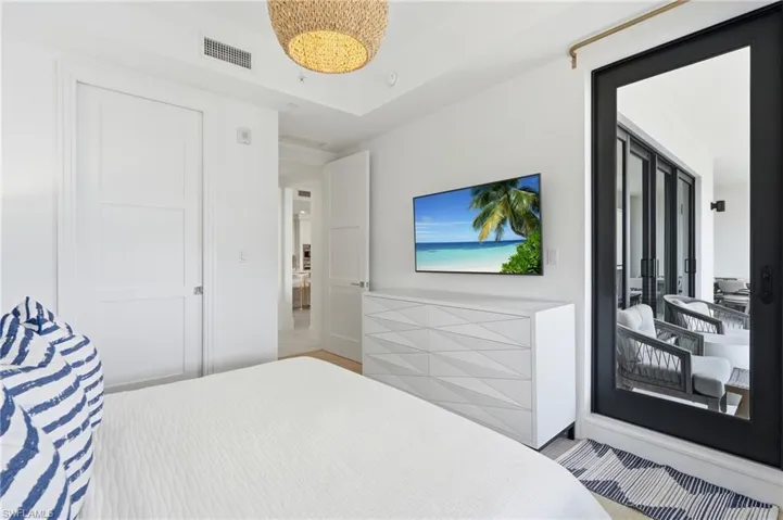 White paneled doors, woven pendant lighting, tray ceiling, and a black-framed sliding glass door to an outdoor area