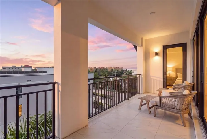 Expansive balcony featuring tile flooring, dark metal railings, and dual exterior wall sconces