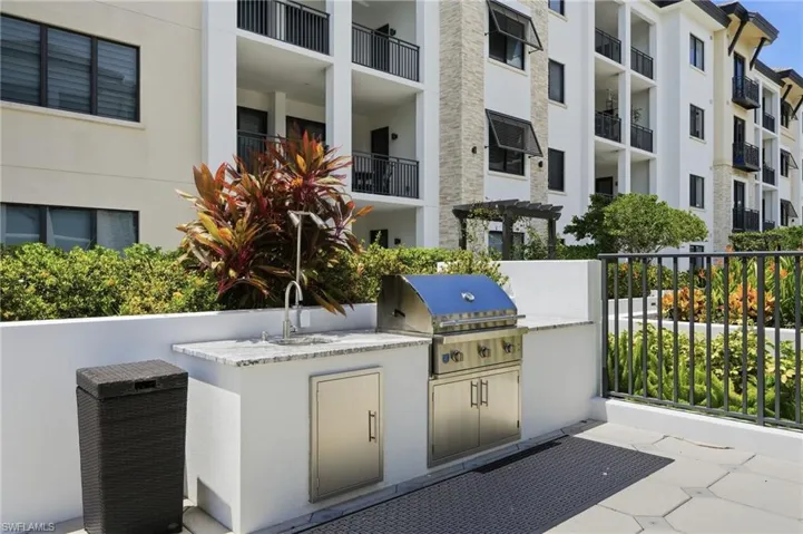 Outdoor kitchen featuring a stainless steel grill, integrated sink, and granite-look countertop