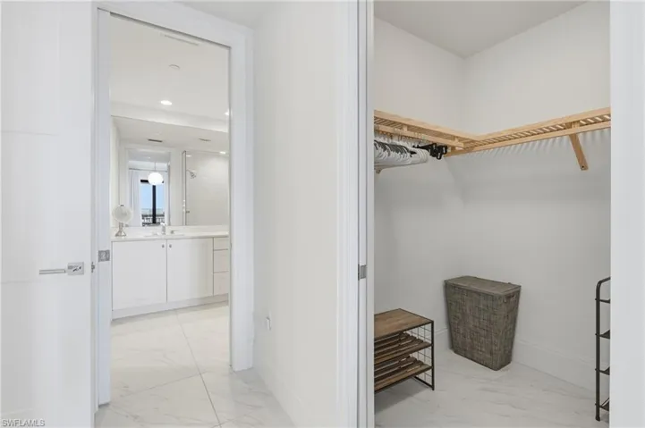 Walk-in closet with built-in shelving, white walls, and light-toned flooring