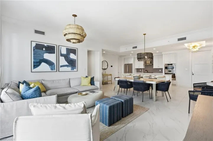 Spacious open-concept living area with high ceilings, recessed lighting, and large format tile flooring