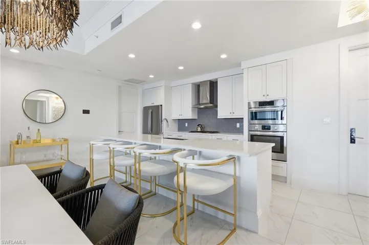Spacious kitchen featuring an expansive island, stainless steel appliances, white cabinetry, and recessed lighting