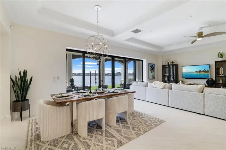 Dining space with crown molding, a raised ceiling, ceiling fan, and a chandelier