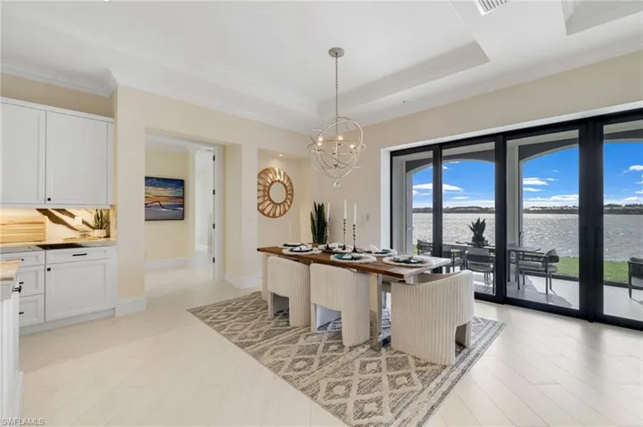 Dining area featuring a water view, a chandelier, crown molding, and a tray ceiling