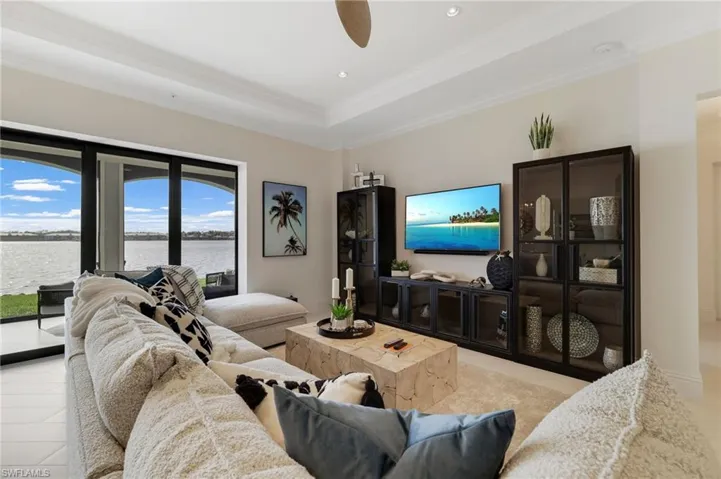 Living area with a raised ceiling, crown molding, ceiling fan, and recessed lighting