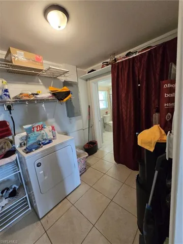 Laundry area with light tile patterned flooring, washer / dryer, and electric panel