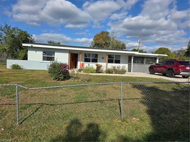 View of front of property featuring a carport and a front yard