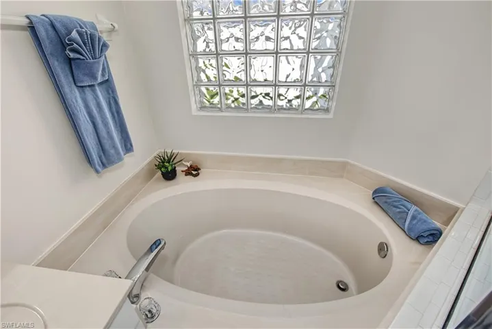 Built-in soaking tub with deck-mounted faucet and a glass block window
