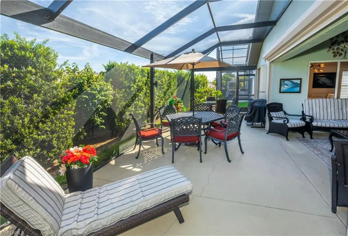 Expansive covered lanai with polycarbonate roof panels and aluminum framing, featuring integrated ceiling fans and recessed lighting