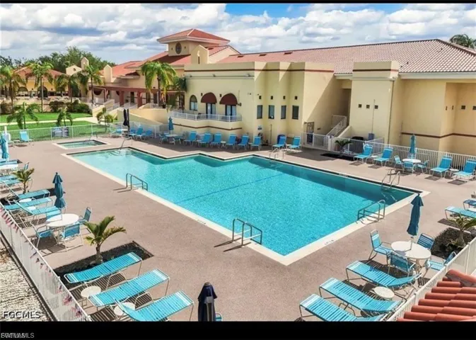 Expansive pool deck featuring a large swimming pool, adjacent hot tub, and surrounding lounge areas