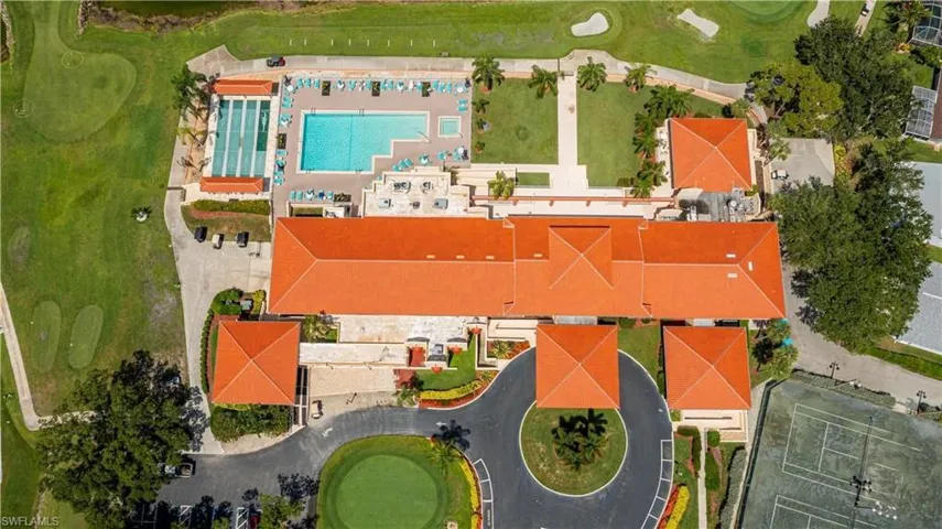 Expansive property featuring a central building with terracotta-style roofing, a large swimming pool, manicured lawns, and tennis courts