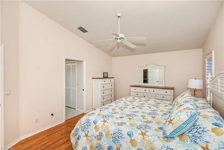 Vaulted ceiling with a ceiling fan, wood-finish flooring, and pocket doors