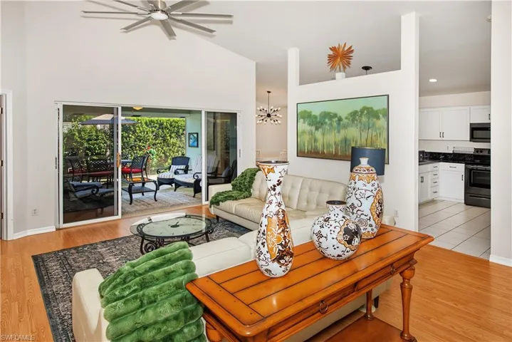 Vaulted ceiling featuring a ceiling fan, wood-finish flooring, and sliding glass doors opening to an outdoor patio