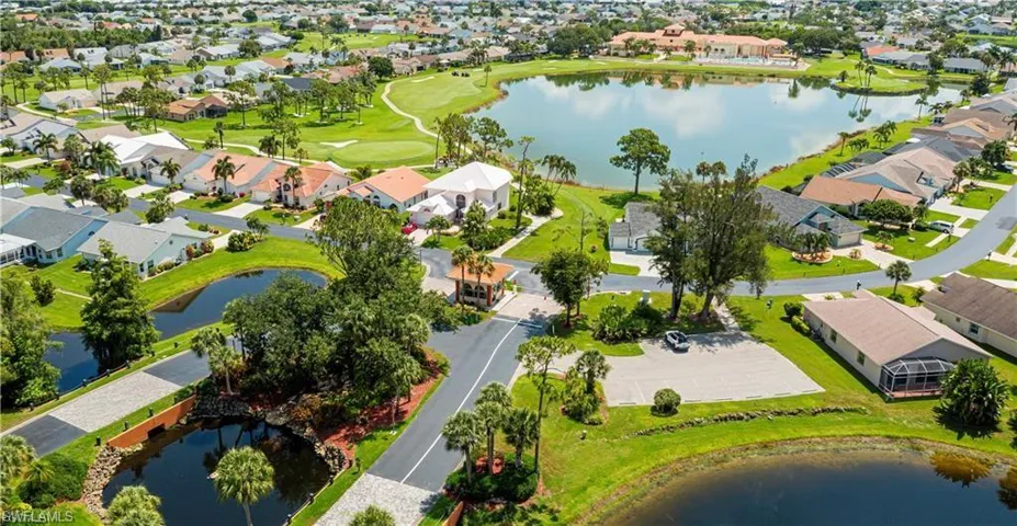 Expansive residential area featuring a golf course, multiple water features, manicured landscaping, and paved roadways