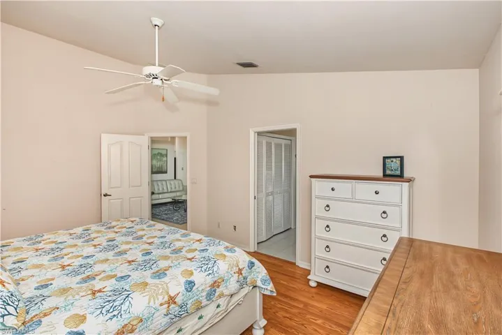 Vaulted ceiling with a ceiling fan, wood-finish flooring, and a paneled door