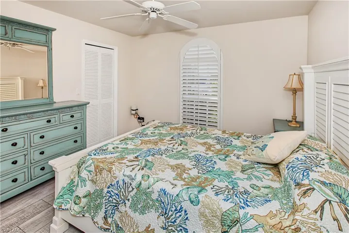 Recessed lighting, ceiling fan, wood-finish flooring, white louvered bifold closet doors, and a white arched window with plantation shutters