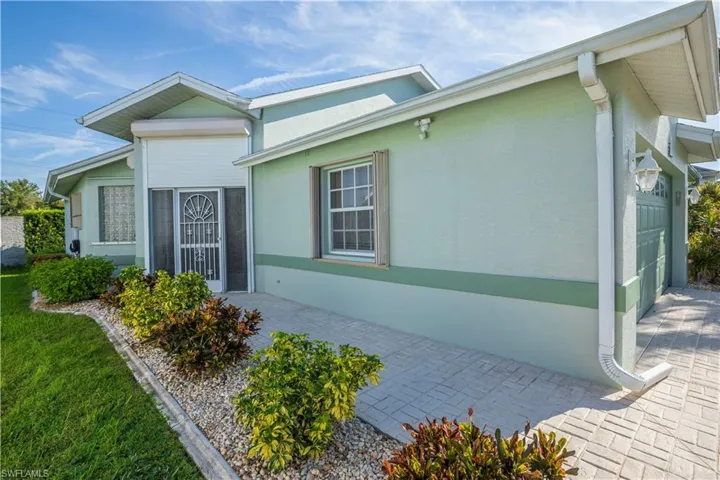 Stucco exterior featuring dual tones, prominent rain gutters, and a garage with an overhead door