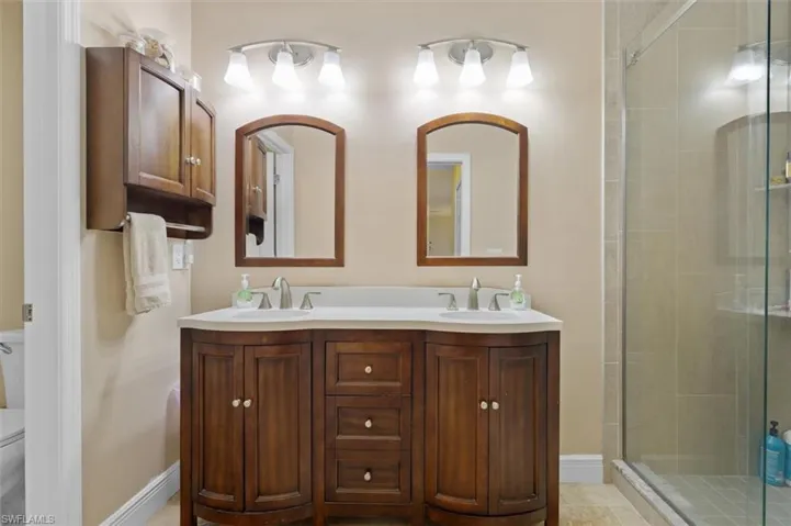 Bathroom with a sink, a shower stall, toilet, and double vanity