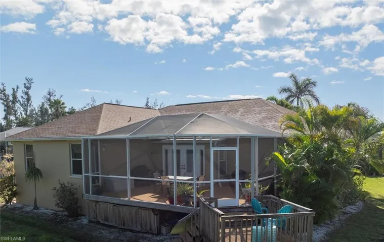 Rear view of property with glass enclosure, a shingled roof, and stucco siding