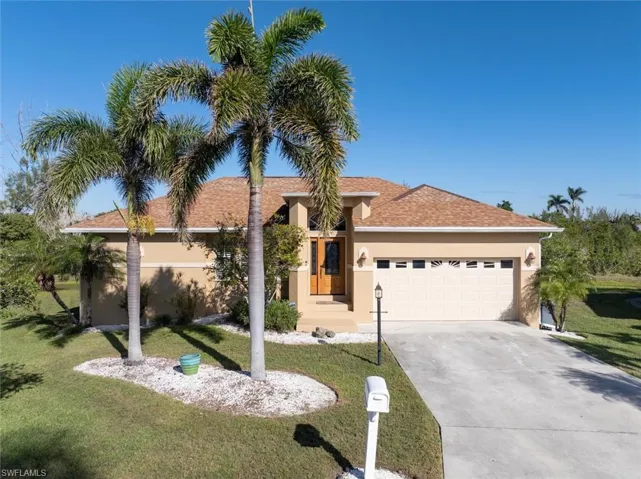View of front of property with a shingled roof, concrete driveway, stucco siding, an attached garage, and a front yard