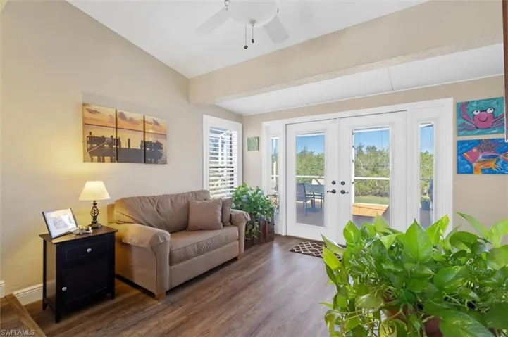 Living area with baseboards, lofted ceiling, ceiling fan, wood finished floors, and french doors