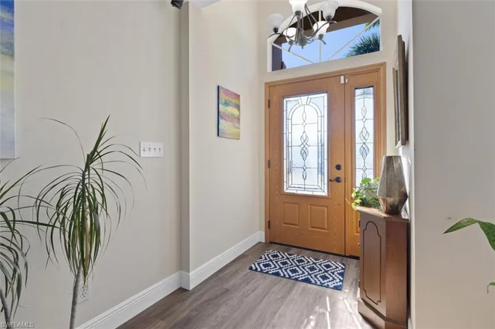 Foyer entrance featuring a healthy amount of sunlight, an inviting chandelier, baseboards, and wood finished floors