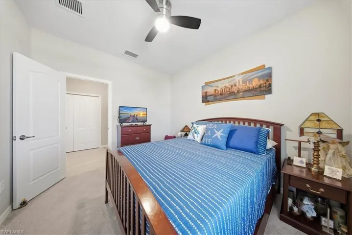 Bedroom with light carpet, ceiling fan, and a closet