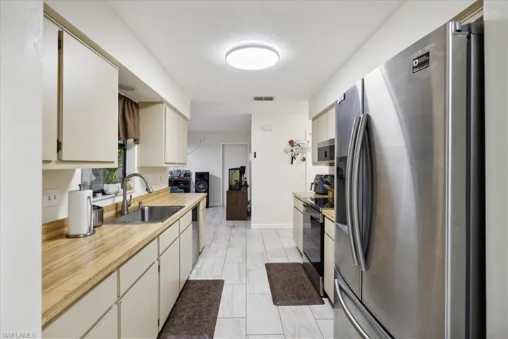 Kitchen featuring light tile patterned flooring, appliances with stainless steel finishes, sink, and cream cabinets