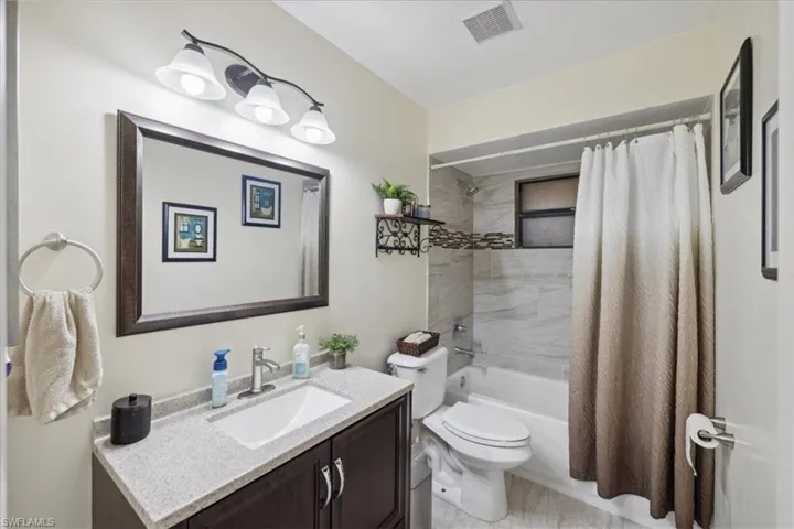 Full bathroom with vanity, shower / bath combo with shower curtain, and toilet