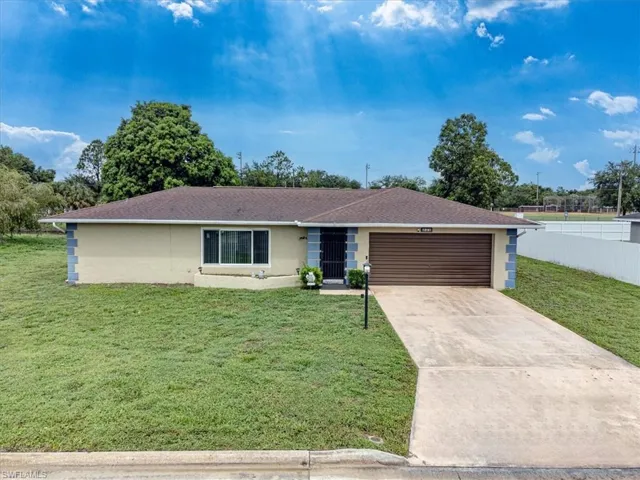 Ranch-style house featuring a garage and a front lawn
