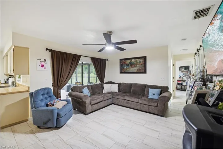 Living room with light tile patterned flooring, sink, and ceiling fan