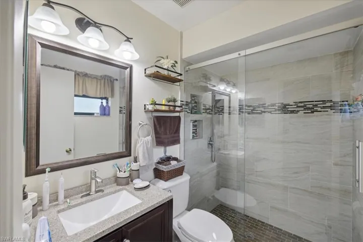 Bathroom with vanity, toilet, and an enclosed shower