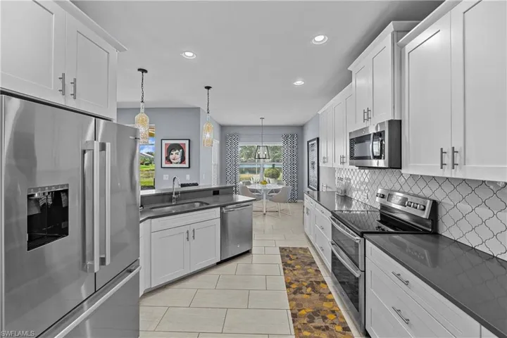 Kitchen with sink, appliances with stainless steel finishes, decorative light fixtures, and white cabinets