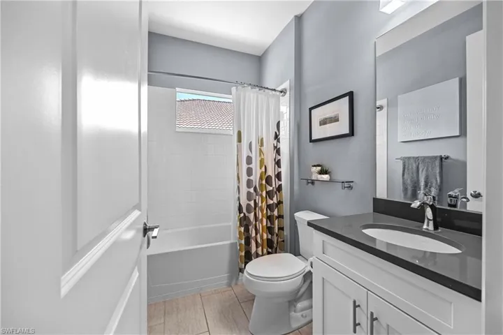 Guest bathroom featuring toilet, vanity, hardwood / wood-style flooring, and shower / bathtub combination with curtain