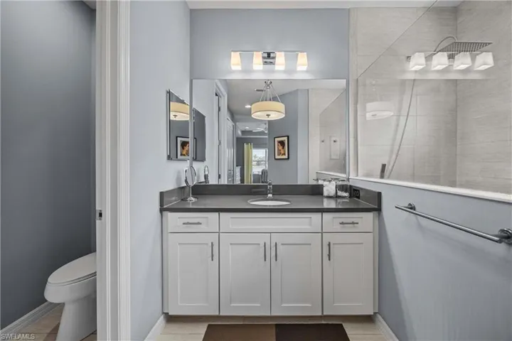 Bathroom featuring separate toilet area.  With vanity, tile patterned floors, and tiled shower