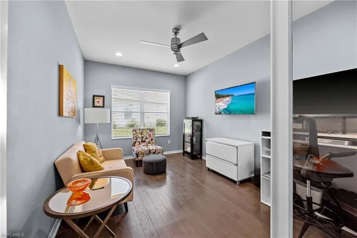 Den with dark hardwood / wood-style flooring and ceiling fan
