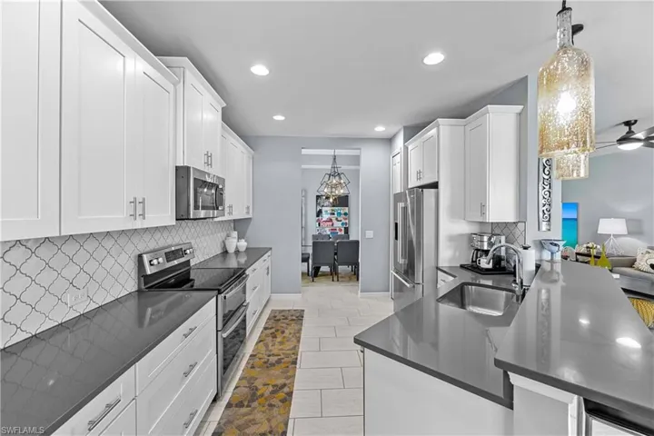Kitchen with white cabinets, sink, pendant lighting, and appliances with stainless steel finishes