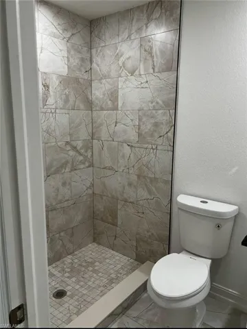 Bathroom with a shower stall and a textured wall