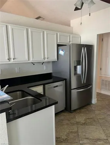 Kitchen featuring dark countertops, white cabinetry, appliances with stainless steel finishes, and ceiling fan