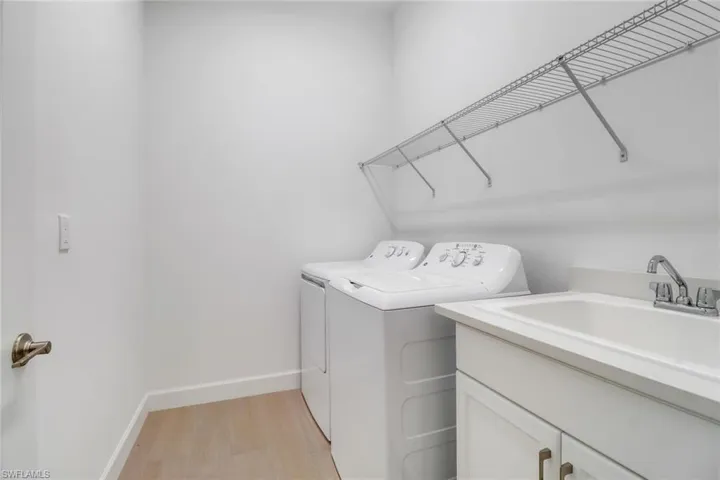 Washroom with cabinets, light hardwood / wood-style floors, separate washer and dryer, and sink