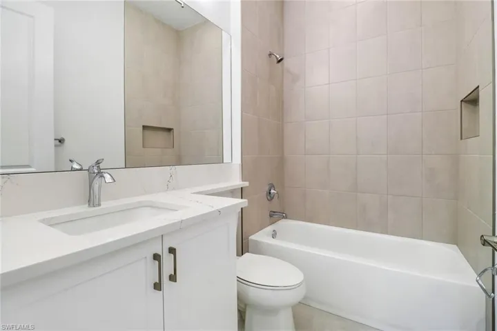 Full bathroom with tiled shower / bath combo, vanity, and toilet