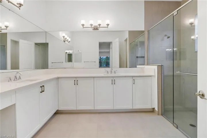 Bathroom with vanity, a shower with shower door, and tile patterned flooring