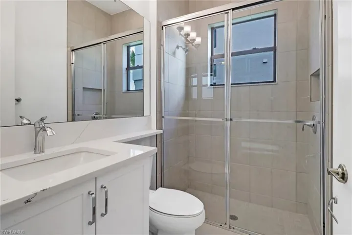 Bathroom with walk in shower, vanity, toilet, and plenty of natural light