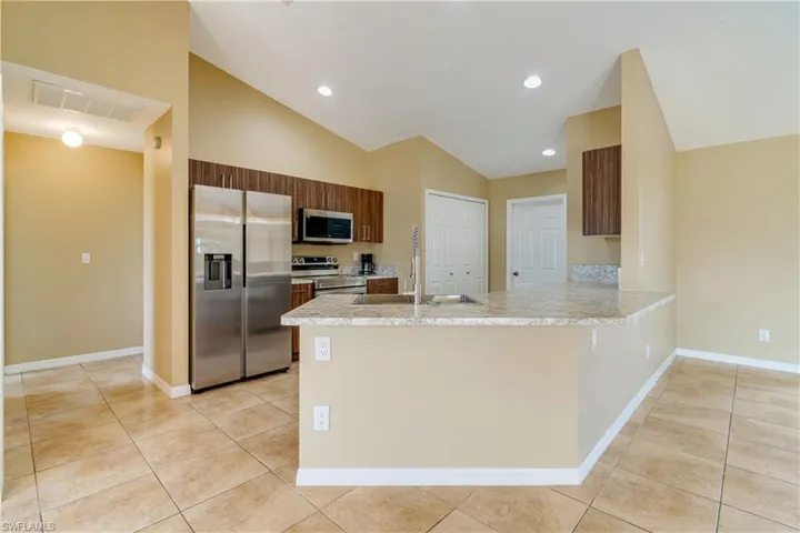 Kitchen featuring vaulted ceiling, kitchen peninsula, appliances with stainless steel finishes, and sink