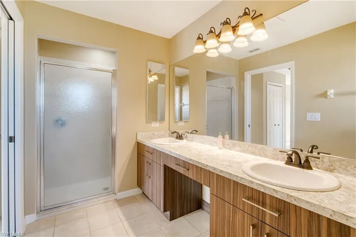 Bathroom with walk in shower, vanity, and tile patterned floors